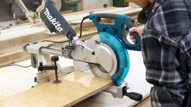 Person cuts plank with radial arm saw