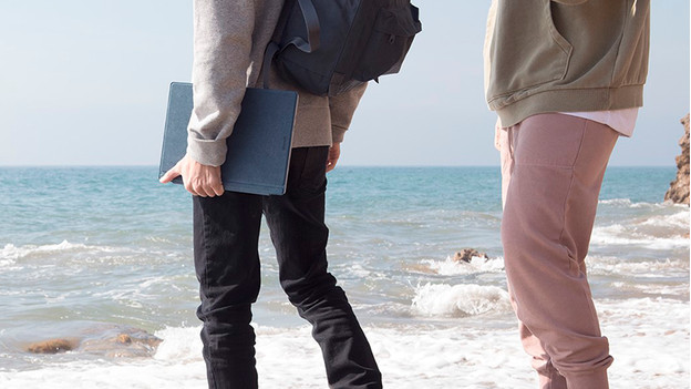 Mann steht mit Laptop am Strand