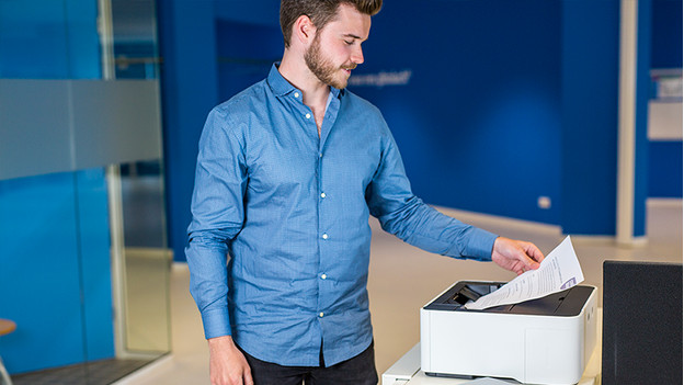 Man happily takes a document from the printer.