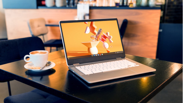 Chromebook on a table with coffee next to it.