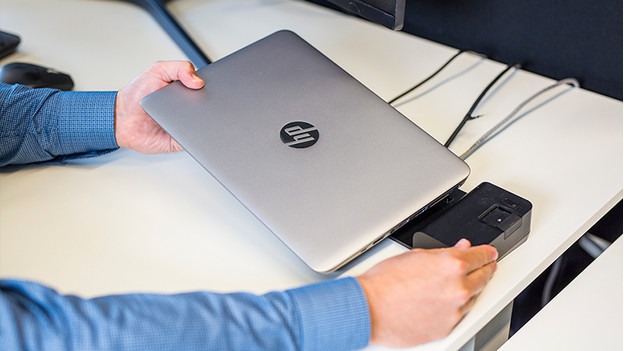 Man puts laptop in docking station.