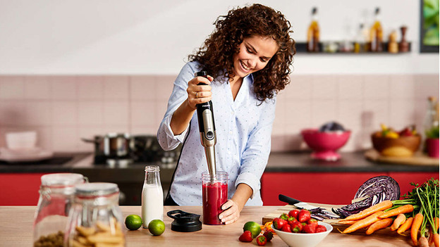 Woman mixes smoothie with immersion blender