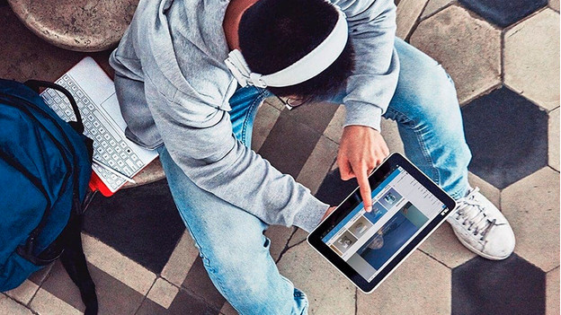 Man with headphones uses touchscreen laptop in tablet mode.