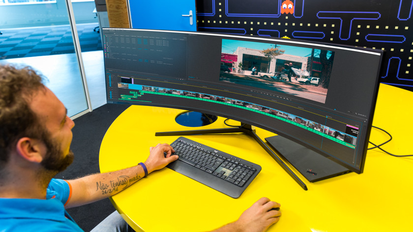 Expert is working in Adobe Premiere Pro on an ultrawide curved 4K monitor