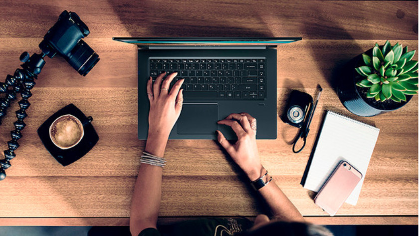 Woman is working on a 17-inch laptop with various accessories on her desk.