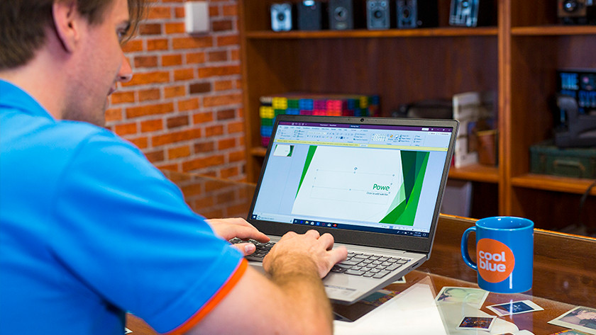 Man working on presentation on laptop with a cup of coffee next to him on the table.