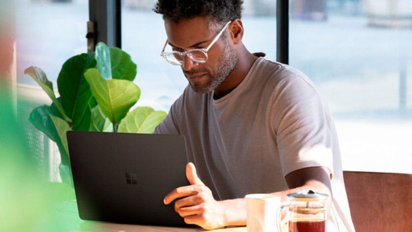 Man is working on a 13-inch laptop in coffee house with plant in the background.