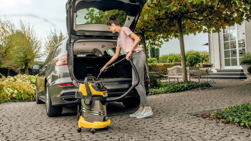 Person uses Kärcher construction vacuum to clean the car.