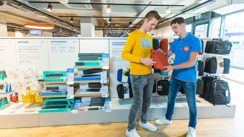 Der Mitarbeiter von Coolblue zeigt dem Kunden im Geschäft die Laptop-Hülle.