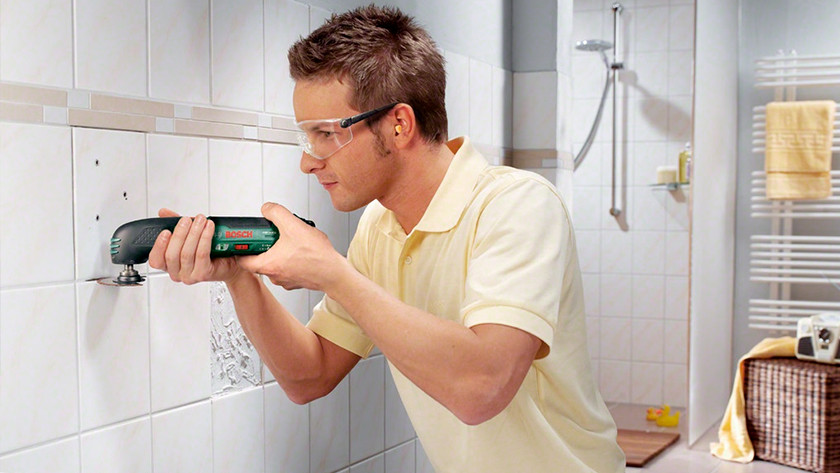 Person removes tiles with oscillating multi-tool