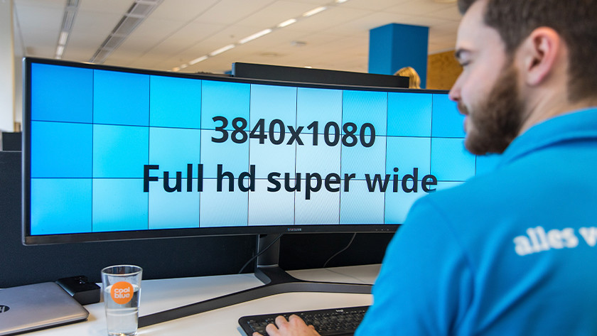 Mann arbeitet am UltraWide-Monitor und schaut sich die Auflösung an