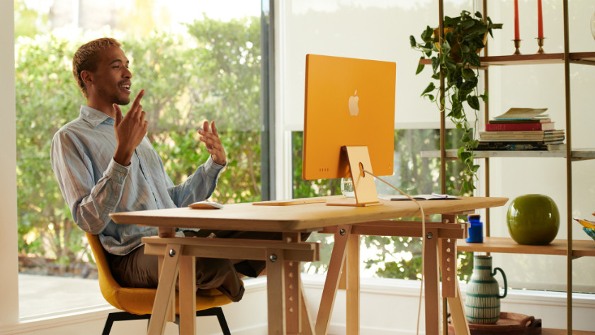 Mann sitzt an Schreibtisch, auf dem ein Apple iMac 24 Zoll steht