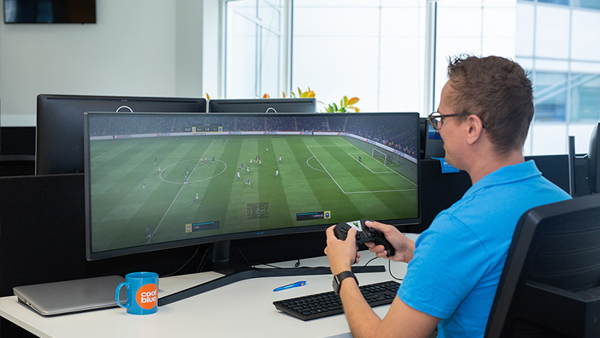 Mann spielt FIFA auf Ultrawide-Monitor für Konsolenspiele