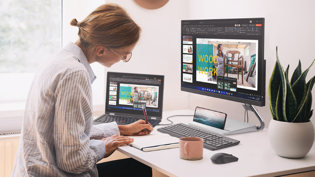 Person works on 15-inch laptop with coffee cup next to her.