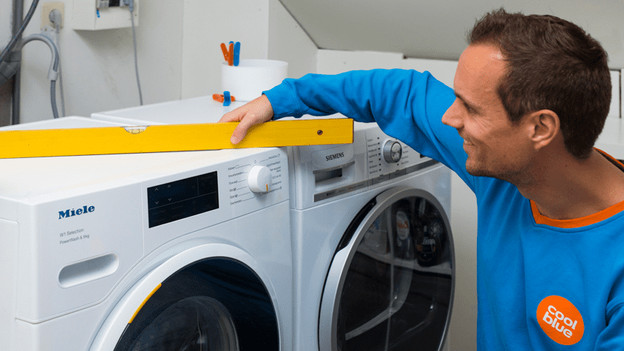 Person with spirit level on washing machine
