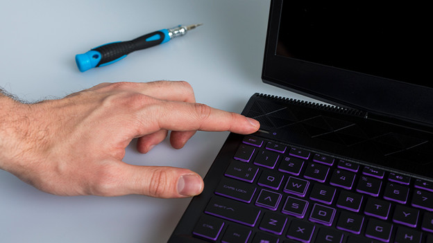 Turn off laptop. Next to the laptop is a screwdriver.