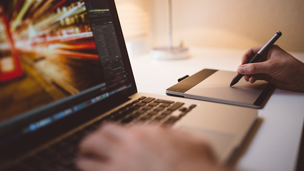 Person arbeitet auf einem Grafiktablett mit Adobe Photoshop.
