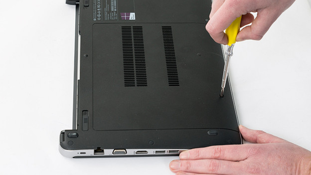 Schraube den Deckel der Unterseite des Laptopgehäuses mit einem Schraubendreher ab.