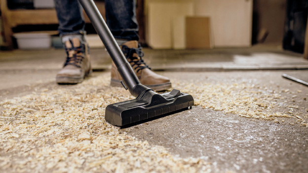 Ein Industriestaubsauger saugt Sägemehl auf