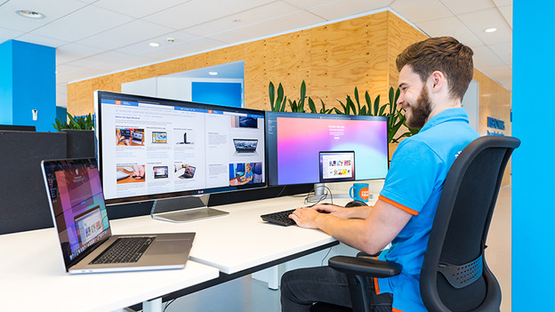 Mann arbeitet an zwei Monitoren mit MacBook