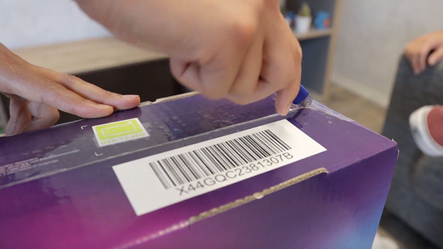 Den Karton mit dem Fernseher mit dem Messer öffnen