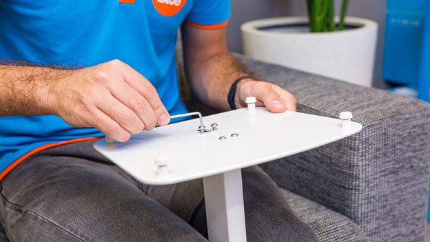 Someone attaches the pole to the base plate of the BlueBuilt speaker stand