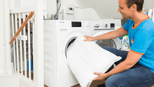 Person putting pillow in washing machine