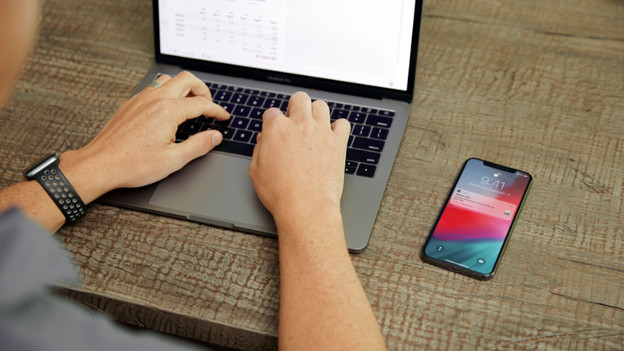 Tippen auf dem Laptop mit dem iPhone daneben