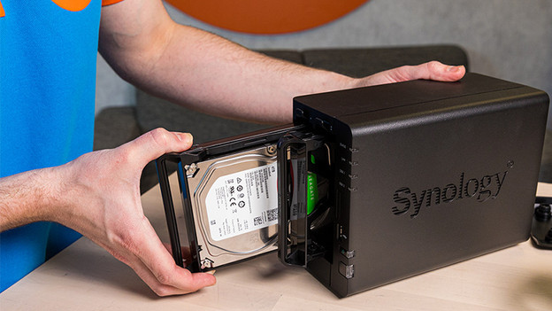 Mann legt Seagate-Festplatte in Synology NAS.